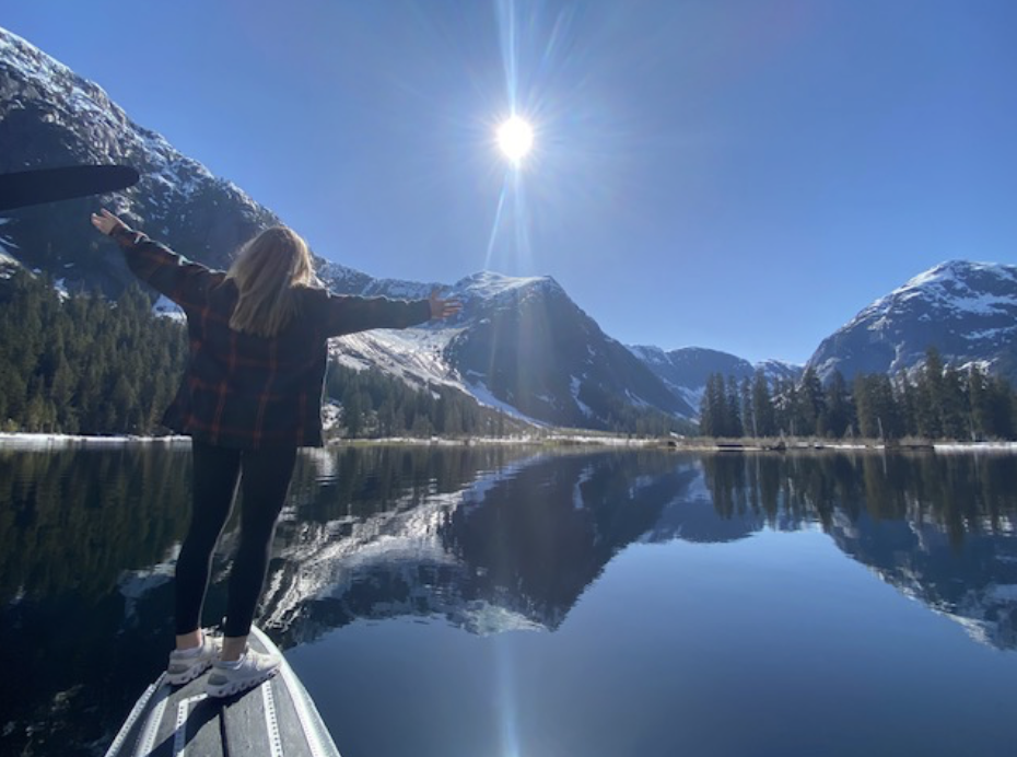 Chef Kerrie posing in front of a picturesque landscape of a lake and mountains