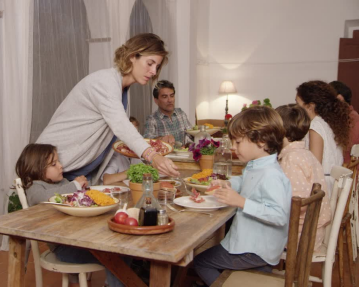 A family with children gathers around the dining table to share a meal together at home.